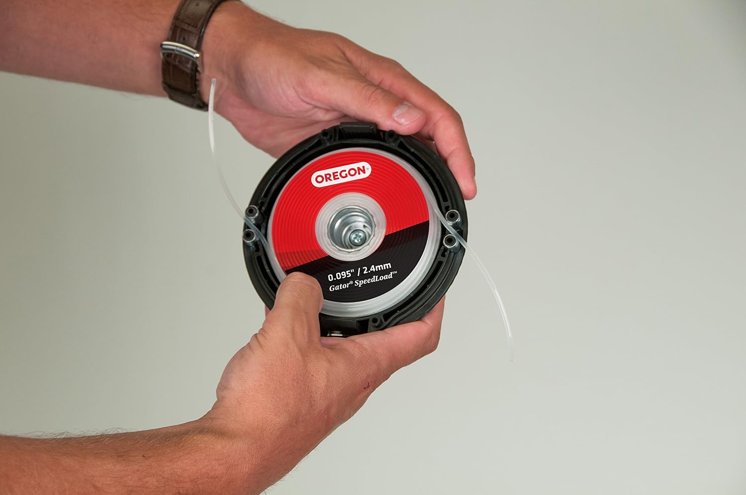 Mani che tengono una testina di ricambio per decespugliatore Oregon Gator SpeedLoad da 0.095 pollici/2.4 mm. Ottima per taglio erba e giardinaggio. Facile da installare e utilizzare, ideale per manutenzione del prato.